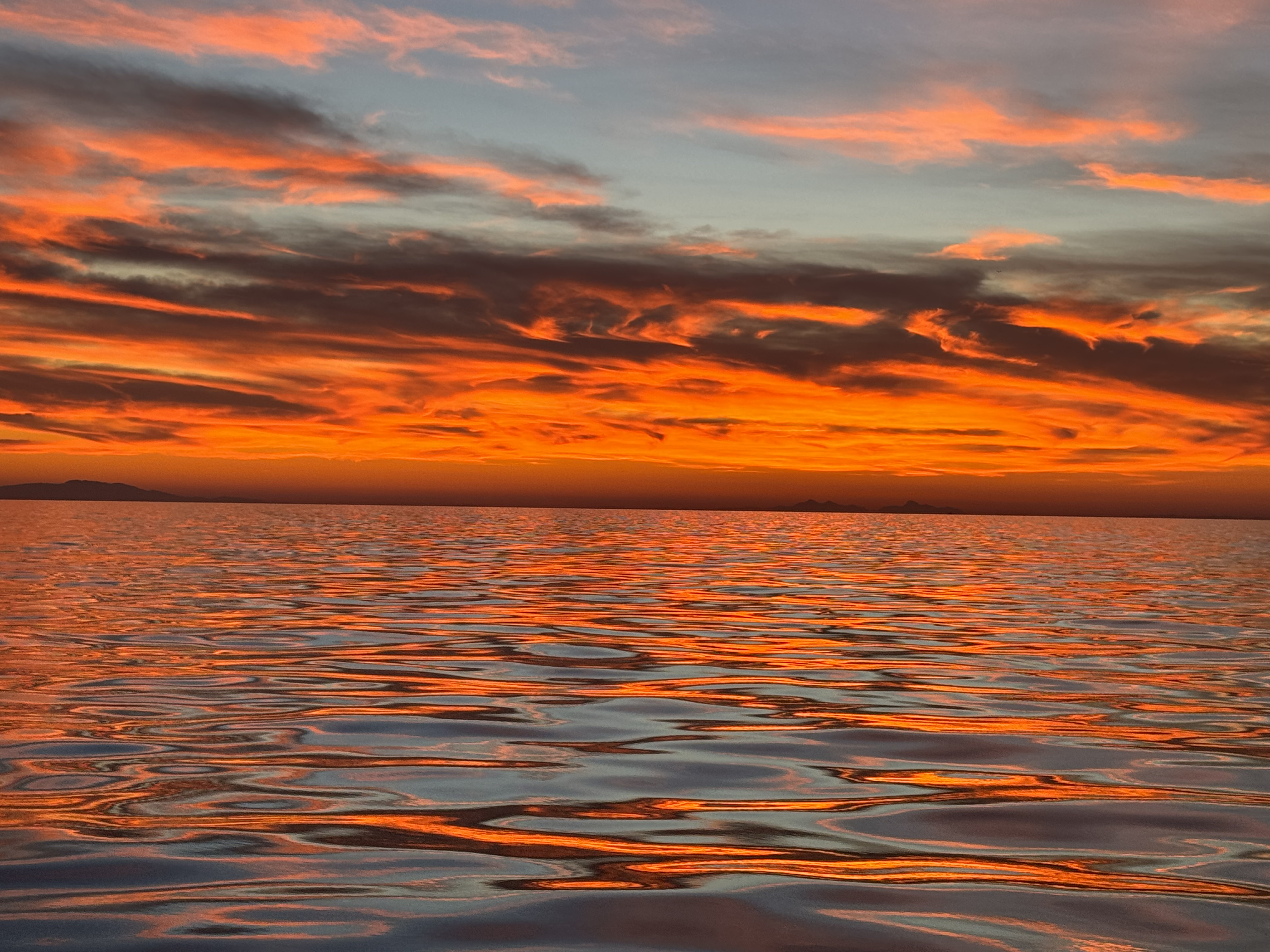 Bright sunset over the lake with a sky full of colors and the water reflecting it back.